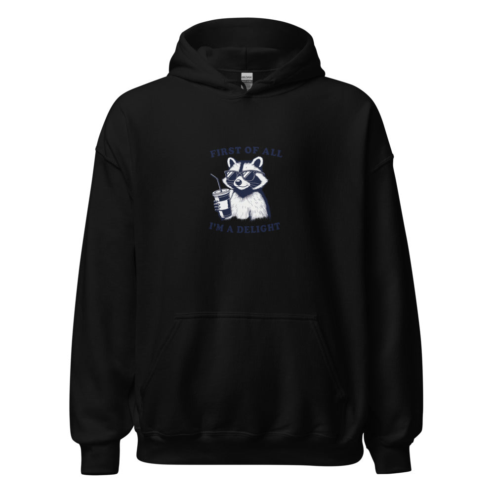 cartoon raccoon wearing sunglasses and holding a coffee cup with 'First of all, I'm a delight' typography Hoodie front view — Wandering With Pride
